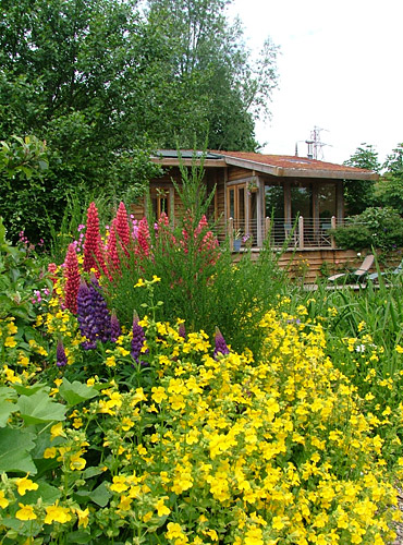 The Waterhouse with beautiful pink, purple and yellow flowers in the foreground